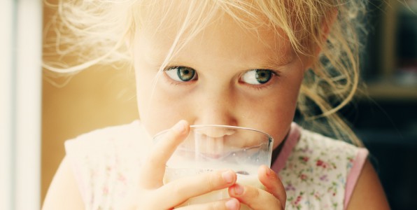 Une petite fille buvant un verre de lait.